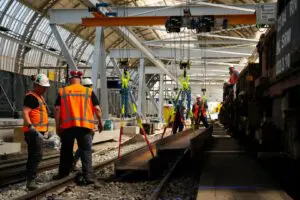 Mensen die in de bouwkuip van Strukton werken met een bovenloopkraan.