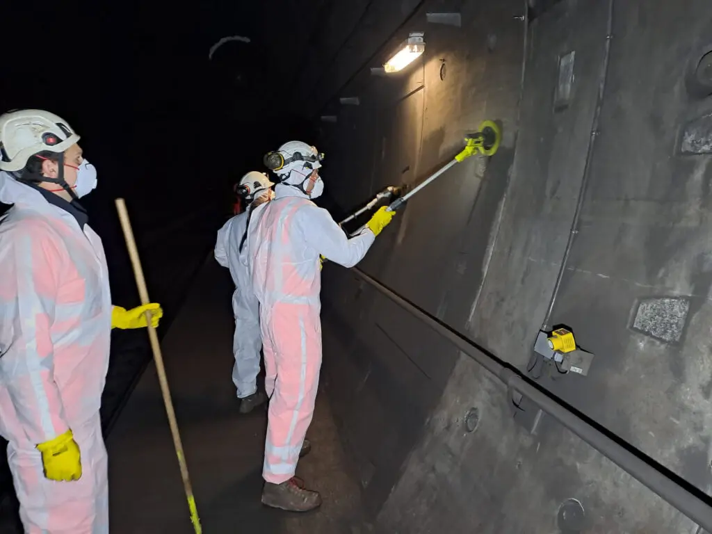 werknemers die tunnelwand schoonmaken in veiligheidskleding